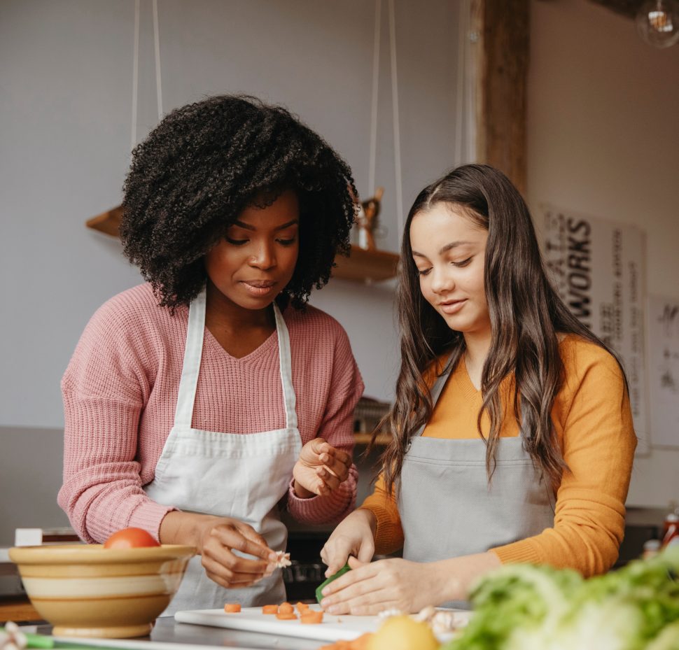 Female chef assisting student in cooking food at class Female chef assisting student in cooking food at class