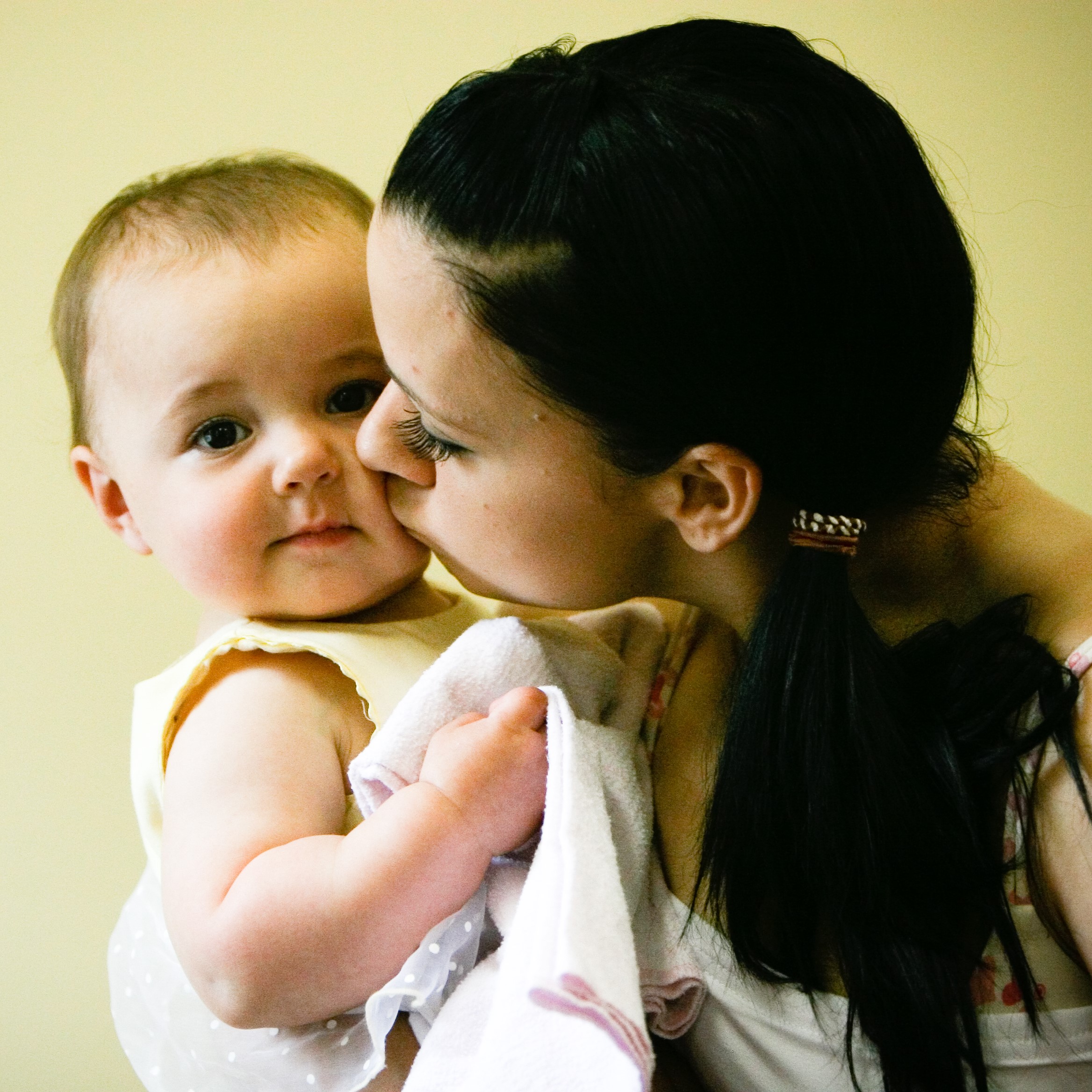 a mother kissing a kid in cheeks