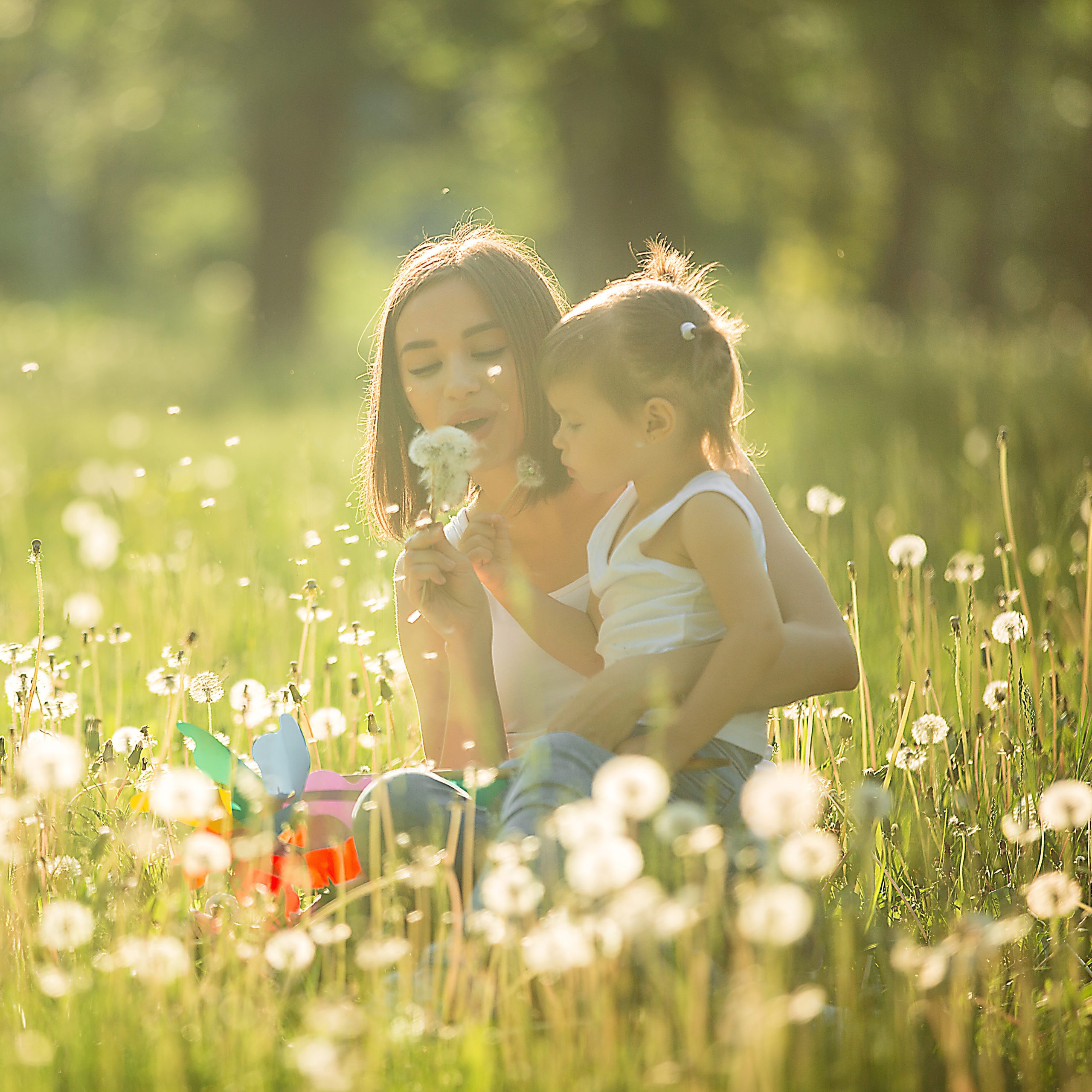 Young mother and her little child playing in the park at summer time.